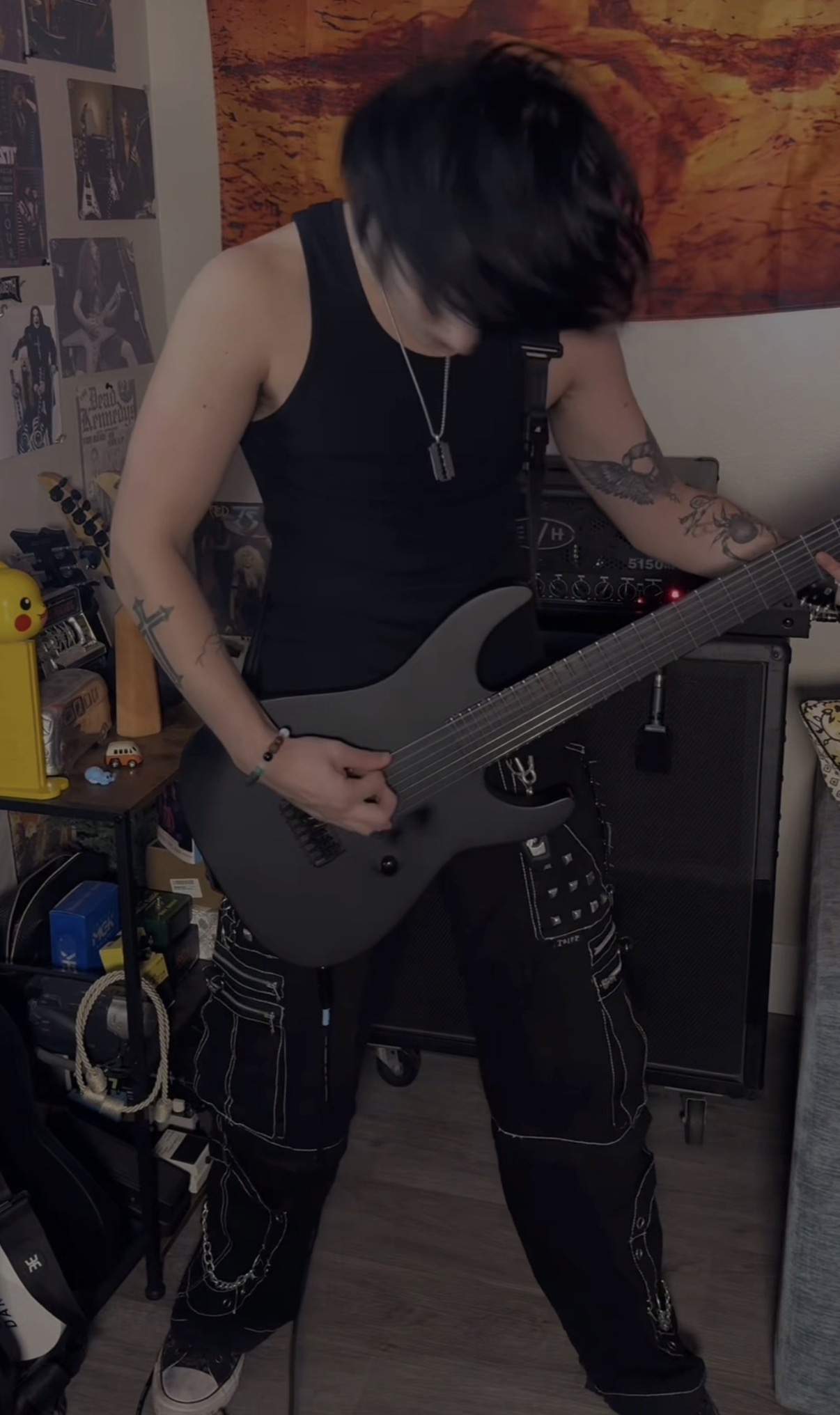 Ryan Dowell standing and playing a black guitar in front of his amp